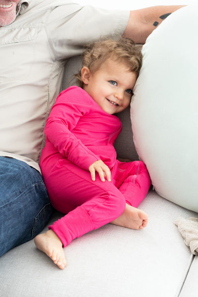 Toddler wearing bamboo zip romper in dragonfruit snuggling dad